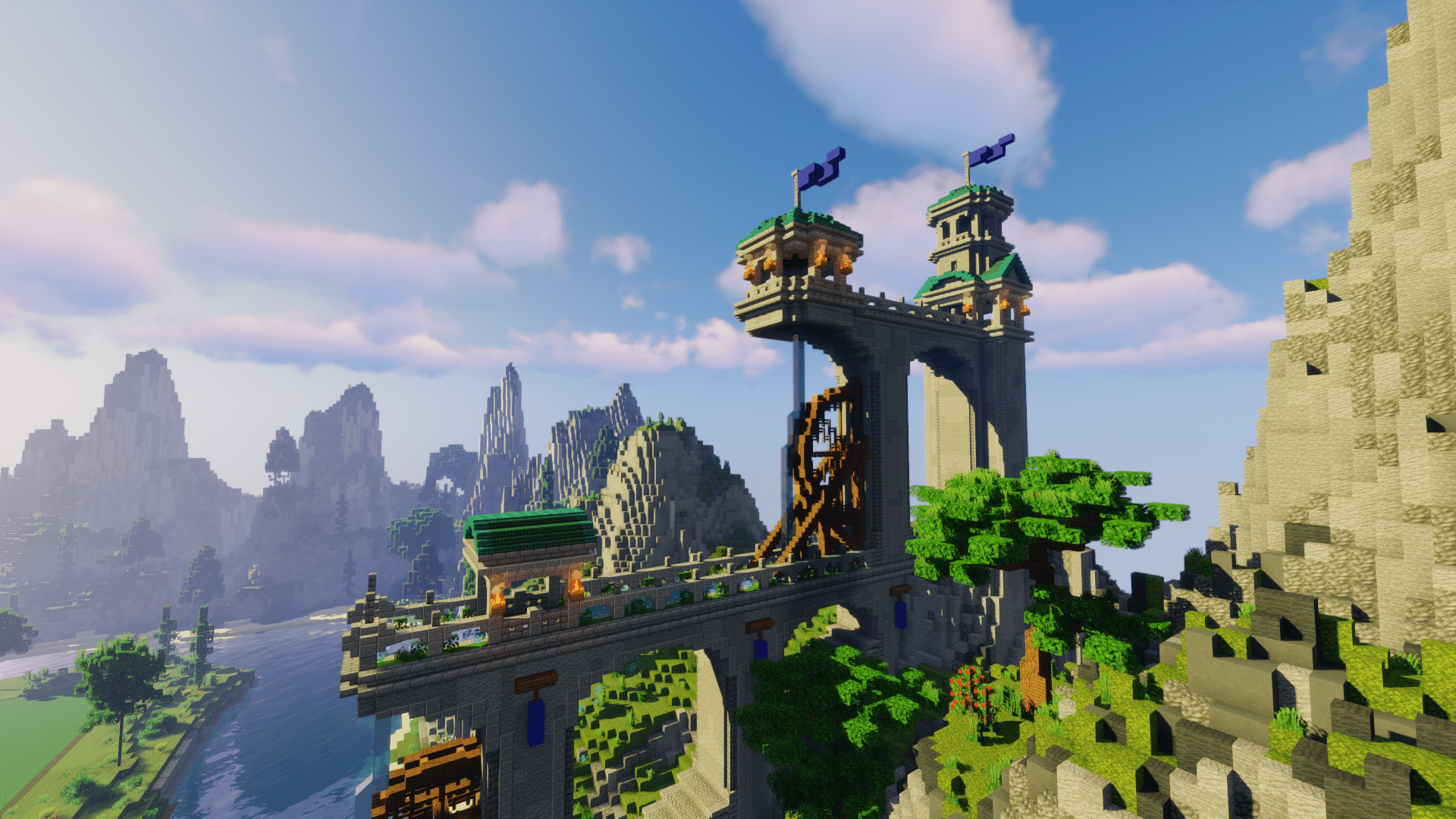 Some mountains with a huge aqueduct with water wheels and tower houses. There are waving flags on the tower houses.